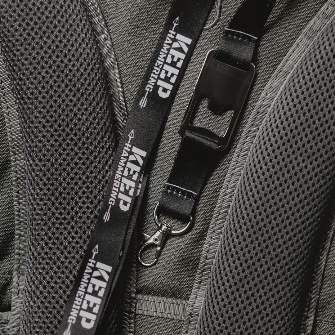 Close-up of a backpack with a black lanyard featuring 'Keep Hammering' text.