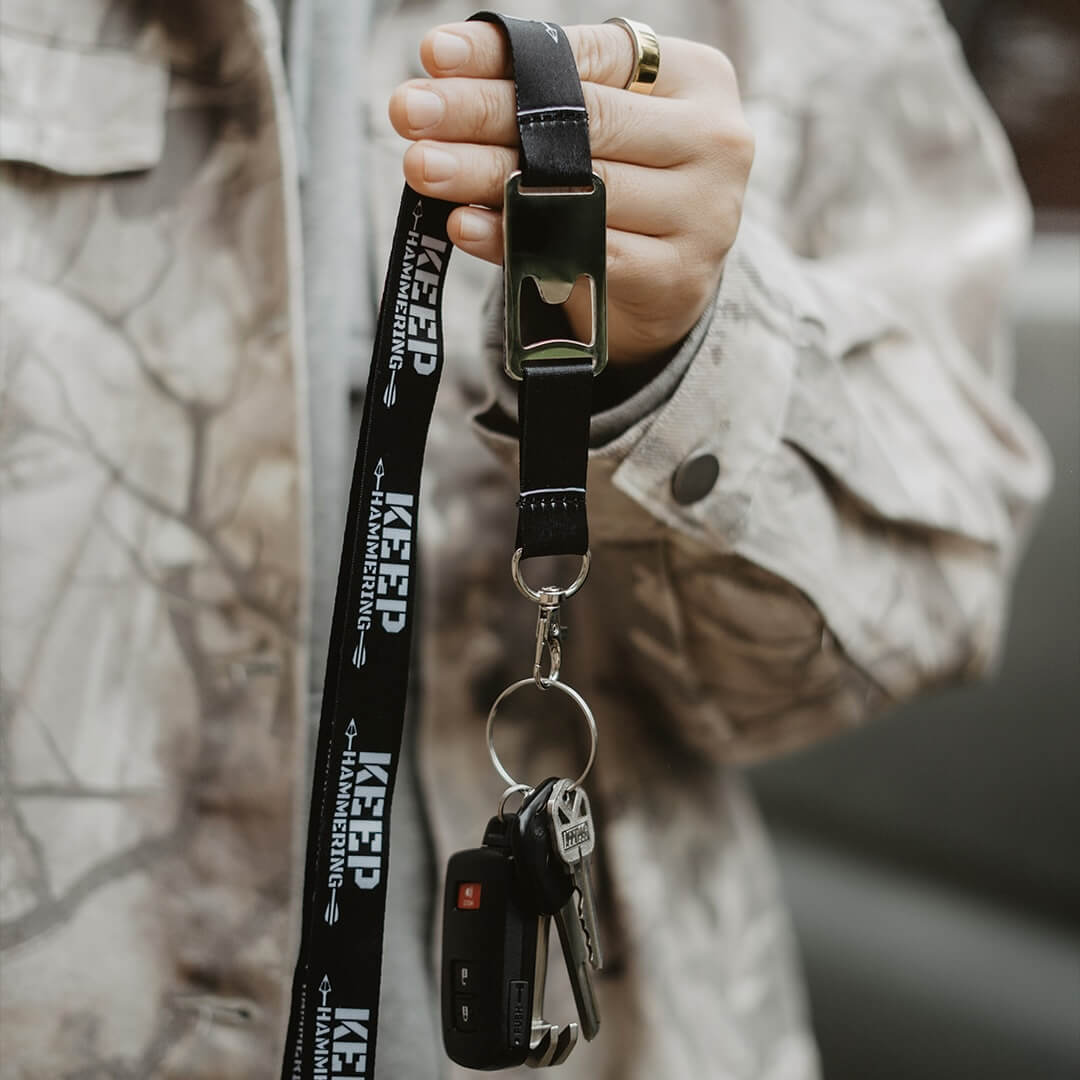 Hand holding a black lanyard with keys, featuring 'KEEP' branding.