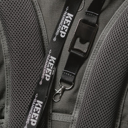 Close-up of a backpack with a black lanyard featuring 'Keep Hammering' text.